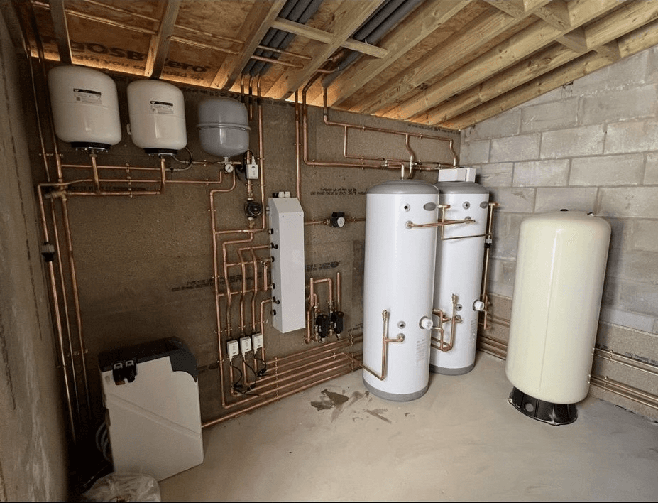 Professional plant room installation with hot water cylinders and copper pipework